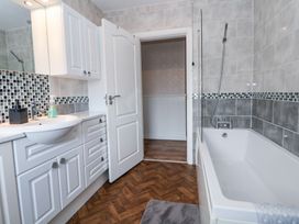 A bathroom with a white sink, white cabinets, a bathtub, and mosaic tile accents at Greenacres in Towyn