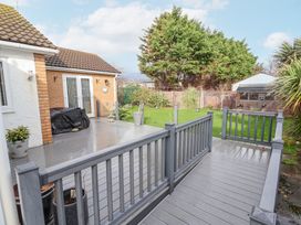 A backyard with a wooden deck patio a lawn plants and a garden shed at Greenacres in Towyn