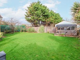 A backyard with a green lawn shed trees and plants at Greenacres in Towyn