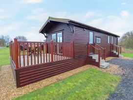 An exterior view of a wooden cabin with a deck and outdoor seating at Cuckoo in Ramsey Huntingdon