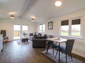 A living room with a gray sofa set a small dining table with two chairs and a TV on a stand at Cuckoo in Ramsey Huntingdon