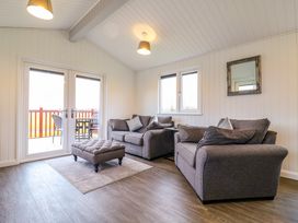 A living room with two gray sofas a matching ottoman and a small table near a window at Cuckoo in Ramsey Huntingdon
