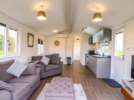 A living room with two sofas a kitchen area with cupboards and appliances and a door at Cuckoo in Ramsey Huntingdon