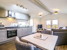 A kitchen and living area with a dining table and chairs a television and patio doors at Cuckoo in Ramsey Huntingdon