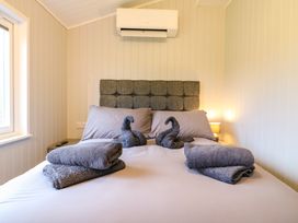 A bedroom with a bed headboard folded towels and towel swans on the bed at Cuckoo in Ramsey Huntingdon