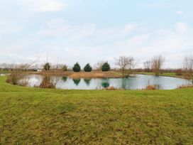 A pond surrounded by grass and trees under a cloudy sky at Cuckoo in Ramsey Huntingdon