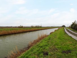 A canal with grassy banks and a dirt road running alongside in a rural area at Cuckoo in Ramsey Huntingdon