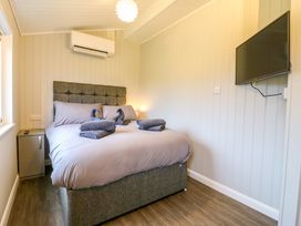 A bedroom with a bed folded towels on it a bedside table an air conditioning unit and a wall mounted television at Cuckoo Ramsey Huntingdon