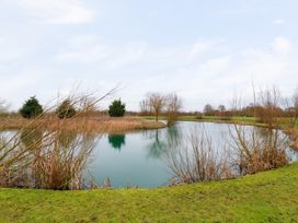 A small lake surrounded by bare trees and grassy banks at Kingfisher in Ramsey Huntingdon