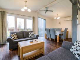 A living room and dining area with two gray sofas a wooden coffee table and a dining table with chairs at Kingfisher Ramsey Huntingdon