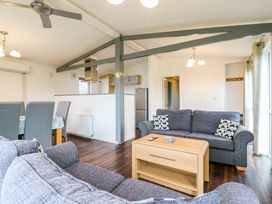 A living room with gray sofas wooden coffee table and dining area with chairs at Kingfisher in Ramsey Huntingdon