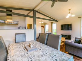 A dining table with four chairs and a patterned tablecloth in an open plan living area with a kitchen and sofas at Kingfisher in Ramsey Huntingdon