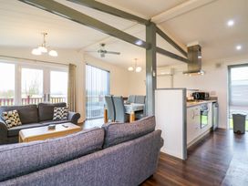 An open-plan living area with sofas a dining table and a kitchen at Kingfisher in Ramsey Huntingdon