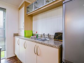 A kitchen with a sink a toaster a green cutting board dish soap and cabinets at Kingfisher in Ramsey Huntingdon