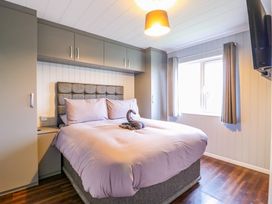 A bedroom with a bed and towels arranged on it with overhead cupboards and a window at Kingfisher Ramsey Huntingdon