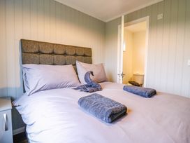 A bedroom with a bed and folded towels with a door open to a bathroom at Kingfisher in Ramsey Huntingdon