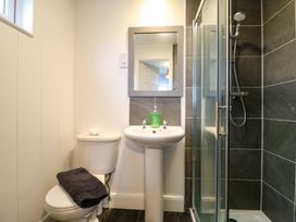 A bathroom with a toilet a pedestal sink with hand soap and a glass shower enclosure at Kingfisher Ramsey Huntingdon