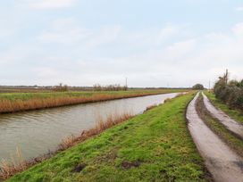 A water canal with grass on both sides and a dirt road next to it at Kingfisher in Ramsey Huntingdon