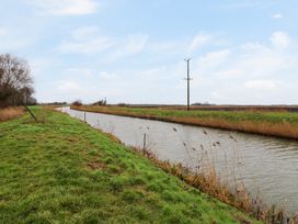 A canal surrounded by grass and reeds with telephone poles in a rural setting at Kingfisher Ramsey Huntingdon