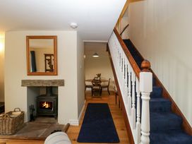 A hallway with a staircase carpeted in blue and a fireplace with a wood burning stove at Court House Cottage Gatcombe near Blakeney