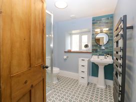 A bathroom with a wooden door patterned floor a pedestal sink mirror towel radiator and a window at Court House Cottage Gatcombe near Blakeney