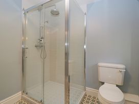 A bathroom with a glass shower enclosure and a white toilet at Court House Cottage in Gatcombe near Blakeney