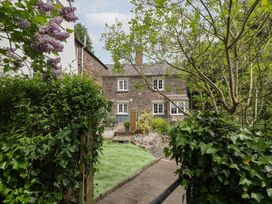 A garden with a house and pathway at Court House Cottage Gatcombe near Blakeney