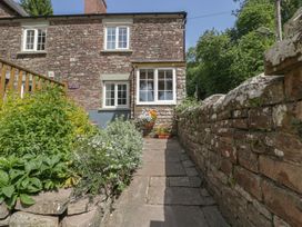 An outdoor path leading to a house with flowers at Court House Cottage in Gatcombe near Blakeney