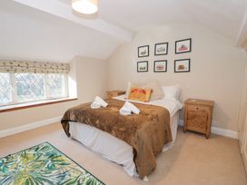 A bedroom with a double bed covered with a brown blanket and white towels on it two wooden bedside tables and framed pictures on the wall at Glandwr Cottage in Llanbedr