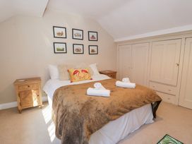 A bedroom with a double bed with folded towels on a brown blanket and framed pictures on the wall at Glandwr Cottage in Llanbedr