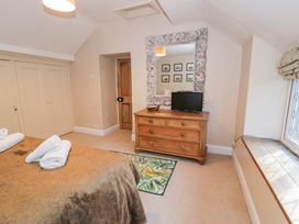 A bedroom with a wooden dresser under a large framed mirror a television on the dresser and a bed with towels on it at Glandwr Cottage in Llanbedr