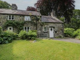 A cottage with a door and windows surrounded by grass and plants at Glandwr Cottage Llanbedr