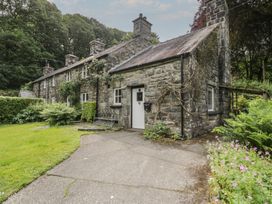 A stone house with a garden and pathway at Glandwr Cottage in Llanbedr