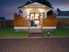 A cabin with wooden railing and steps leading to a front porch with open doors at Binevanagh Cabin in Magilligan near Castlerock