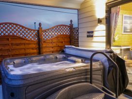 An outdoor hot tub with water jets active next to a wooden privacy fence and the entrance of a cabin at Binevanagh Cabin in Magilligan near Castlerock