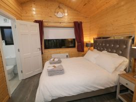 A bedroom with a bed towels on it bedside tables lamps wooden walls and an open door to a bathroom at Binevanagh Cabin in Magilligan near Castlerock