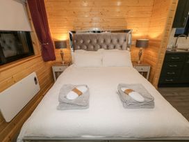 A bedroom with a bed with white bedding two bedside tables with lamps and folded towels with slippers on the bed at Binevanagh Cabin in Magilligan near Castlerock