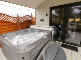 An outdoor hot tub with bubbling water on a deck next to a wooden privacy fence and a glass door at Binevanagh Cabin in Magilligan near Castlerock