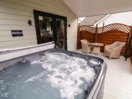 A covered outdoor area with a hot tub and a table with two wicker chairs at Binevanagh Cabin in Magilligan near Castlerock