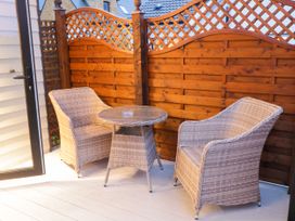 A small patio with two wicker chairs and a matching round table next to a wooden fence at Binevanagh Cabin in Magilligan near Castlerock