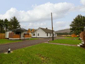 A white house with a gravel driveway surrounded by grass and trees at Binevanagh Cabin in Magilligan near Castlerock