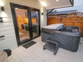 An outdoor deck area with a hot tub steps and glass double doors leading inside at MUSSENDEN CABIN Magilligan near Castlerock