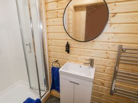 A bathroom with a shower cubicle a white sink with cabinet a round mirror and a towel rack at MUSSENDEN CABIN Magilligan near Castlerock
