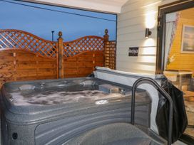 An outdoor hot tub with wooden lattice fencing and an open door to a room at Benone Cabin Magilligan near Castlerock