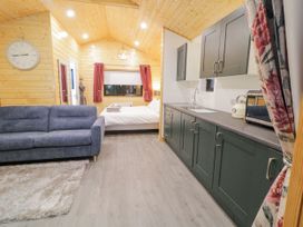 An open room with a blue sofa rug kitchen cabinets and a bed inside Benone Cabin in Magilligan near Castlerock