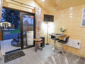 A small dining area with two stools a wall-mounted television and glass sliding doors leading outside at Benone Cabin in Magilligan near Castlerock