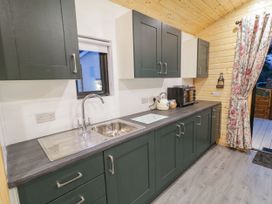 A kitchen with dark cabinets stainless steel sink toaster kettle and floral curtain at Benone Cabin in Magilligan near Castlerock