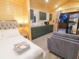 A room with a bed a sofa a kitchen area with cabinets and a sliding glass door at Benone Cabin in Magilligan near Castlerock
