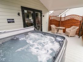 An outdoor patio with a bubbling hot tub a small table and two wicker chairs at Benone Cabin in Magilligan near Castlerock