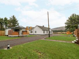 A driveway with grass on both sides and a white house and a porch at Benone Cabin Magilligan near Castlerock